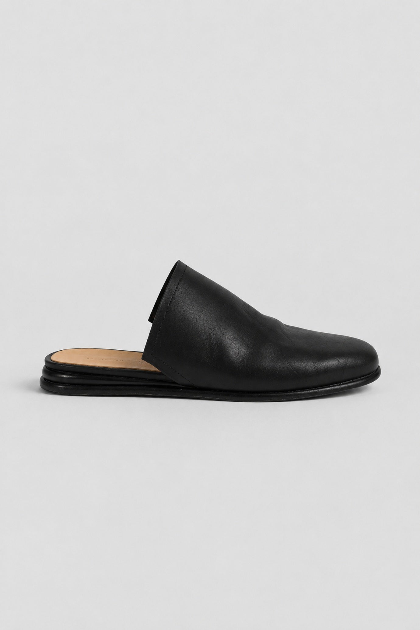 A single black leather mule slipper with a square toe and low flat sole, shown in profile against a light gray background.