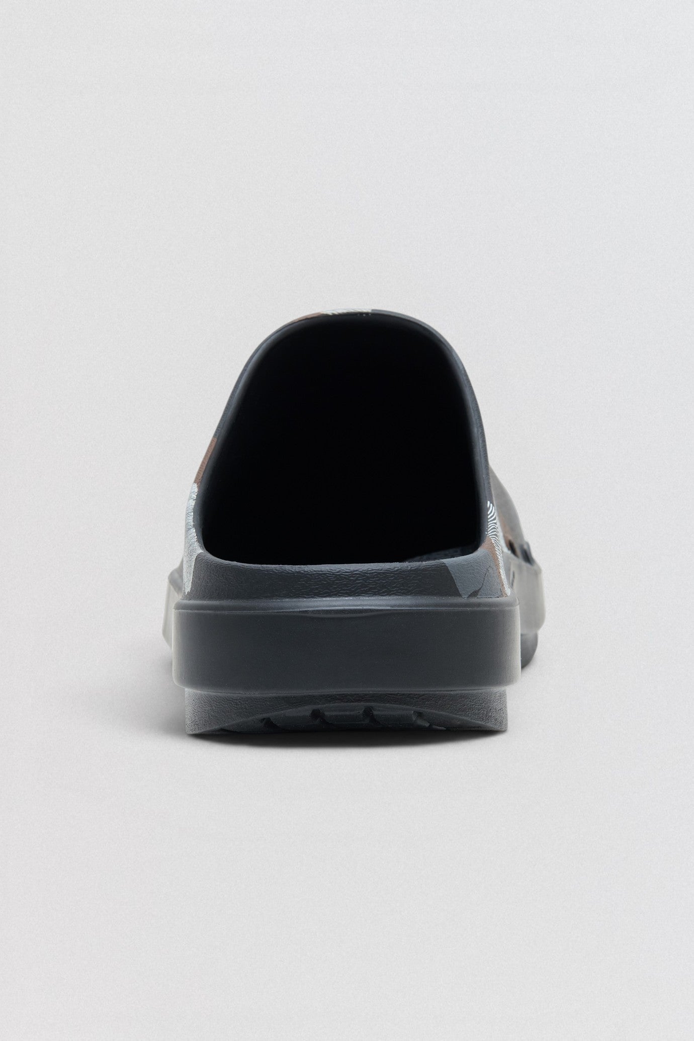 Undercover x OOFOS Black slip-on shoe on a light gray background