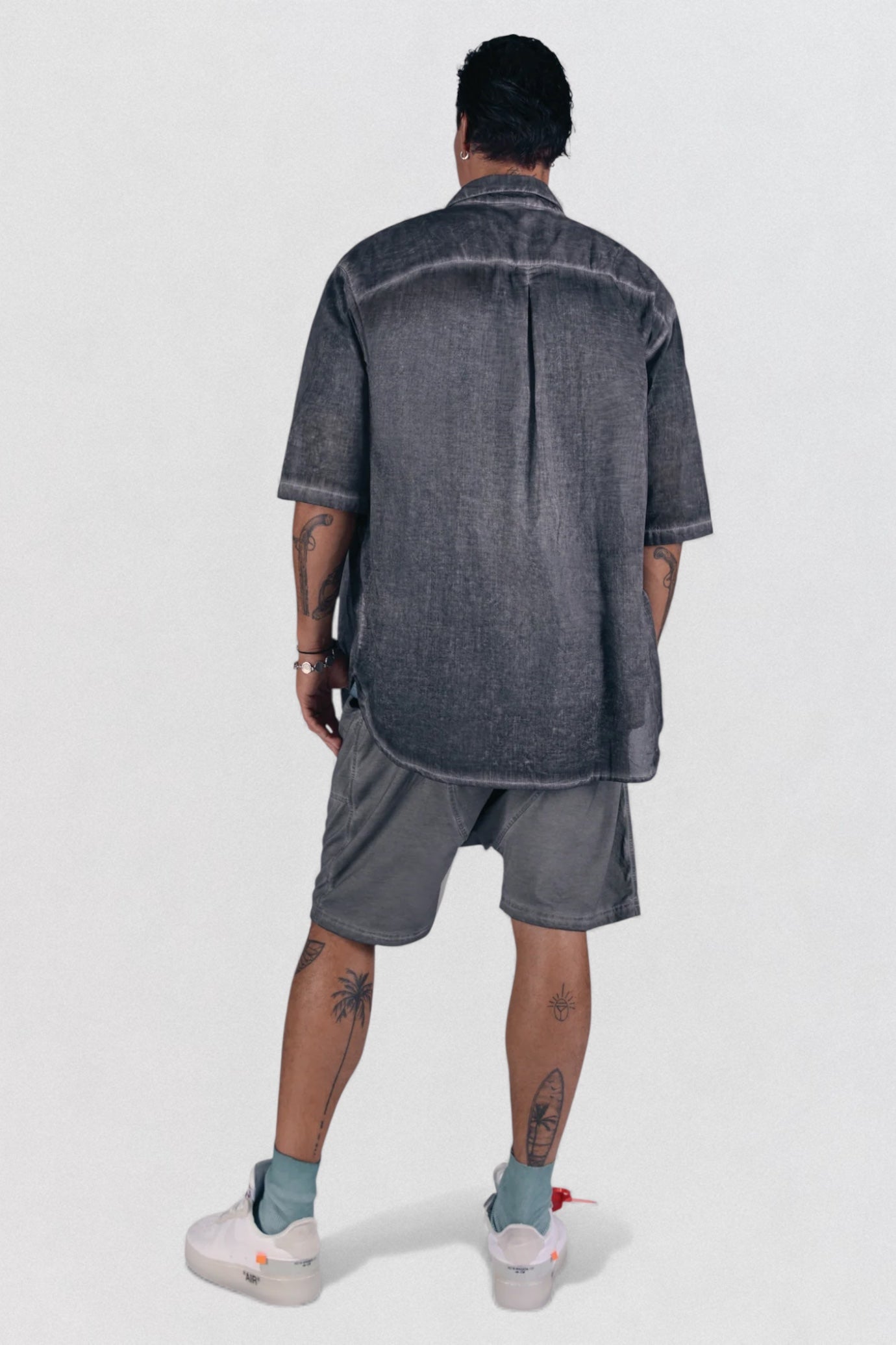 Person wearing a gray shirt and shorts set on a white background