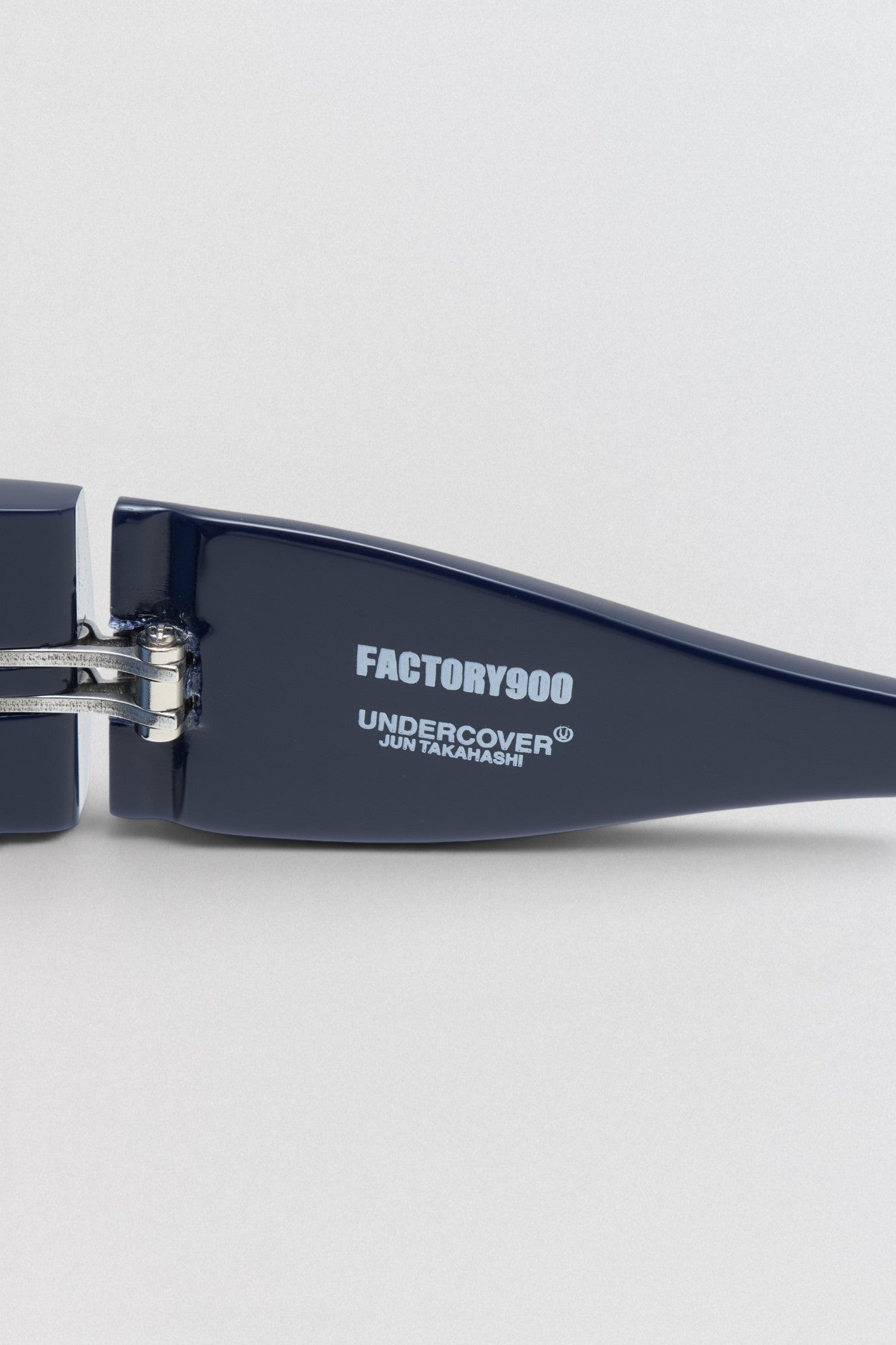 Undercover SS26 Factory900  Navy sunglasses with 'Factory900' and 'Undercover' branding on a light gray background