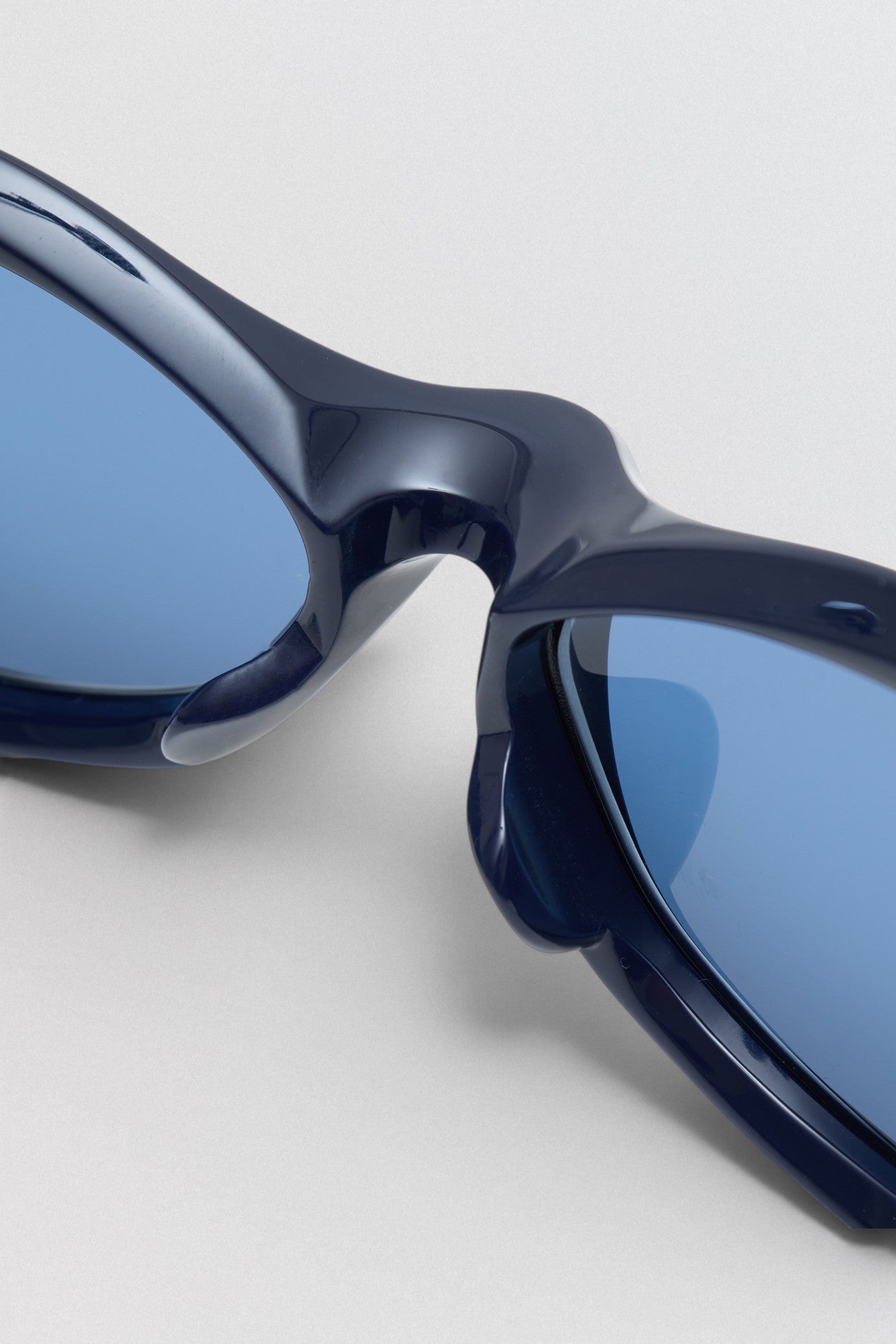 Undercover SS26 Factory900  Blue sunglasses on a light gray background