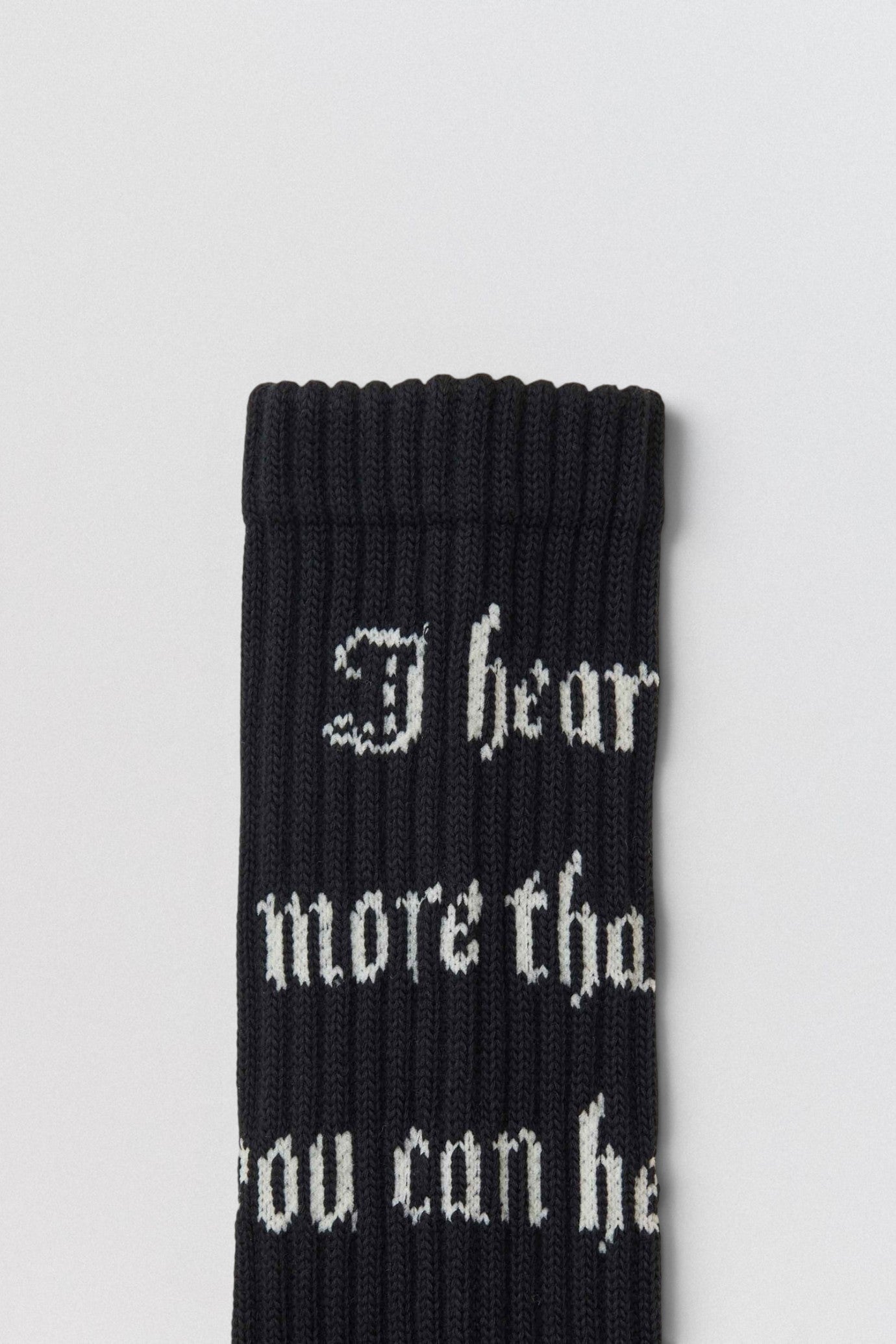 Undercover SS26 Logo Black sock with white text on a light gray background