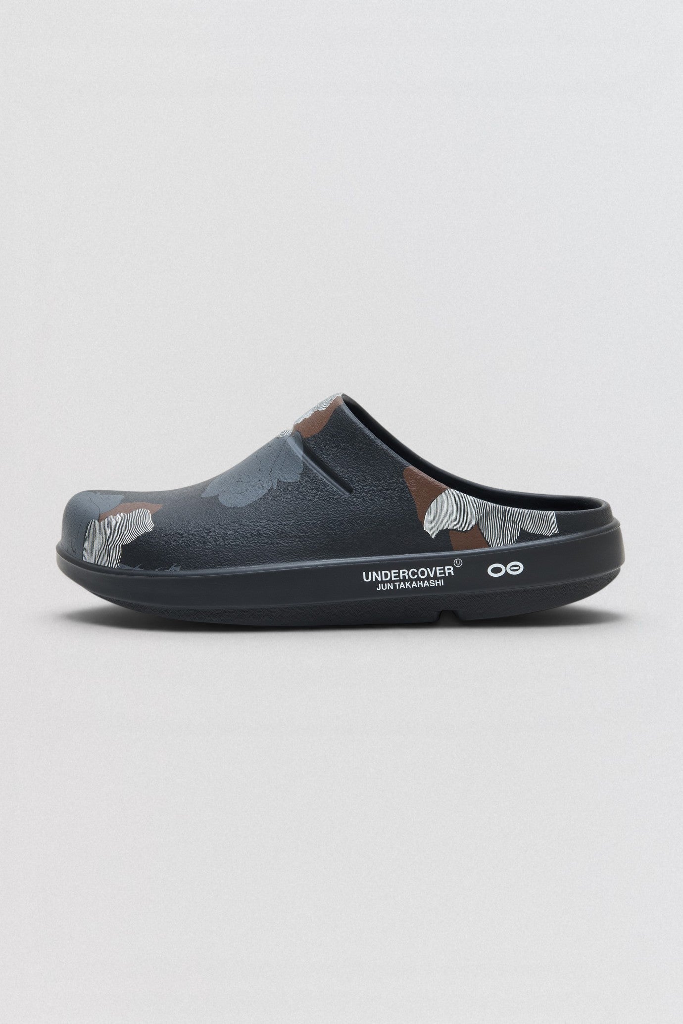 Undercover x OOFOS  Clog shoe with camouflage pattern on a light gray background