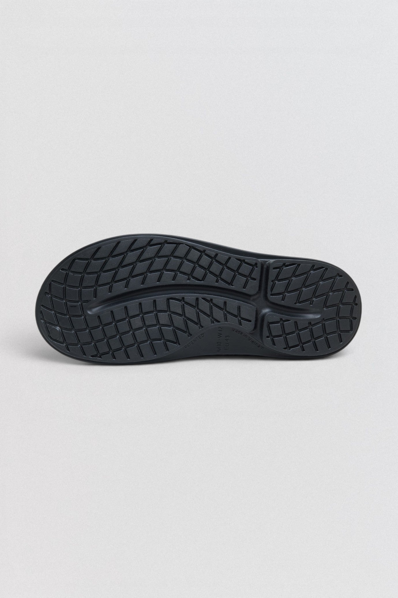 Undercover x OOFOS  Black sole of a shoe on a light gray background