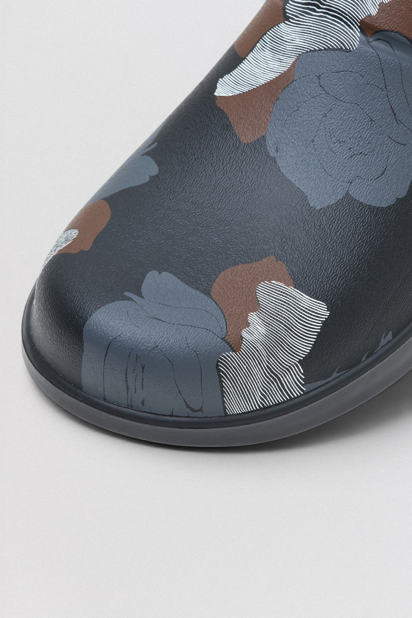 Undercover x OOFOS  Floral-patterned slip-on shoe on a light gray background