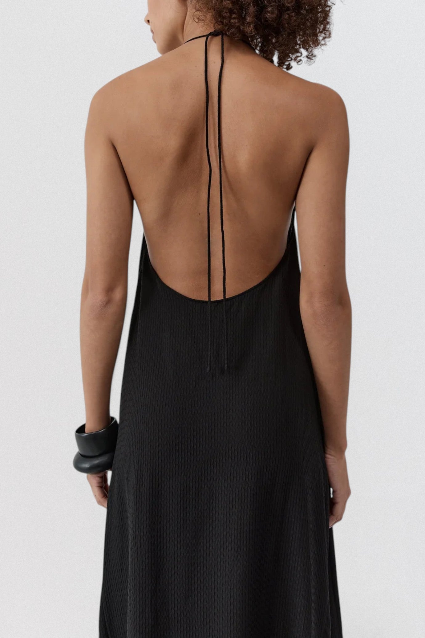 ST. AGNI Textured Weave Halter Dress in black with square halter neckline and asymmetric handkerchief hem