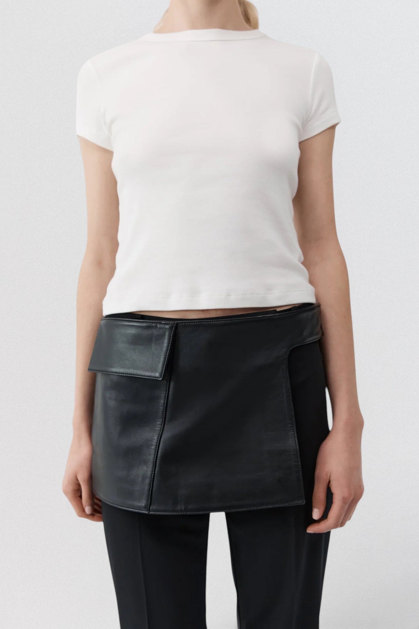 ST. AGNI Utility Skirt Belt in black lambskin leather with fold-over waistband and side cut-out detail