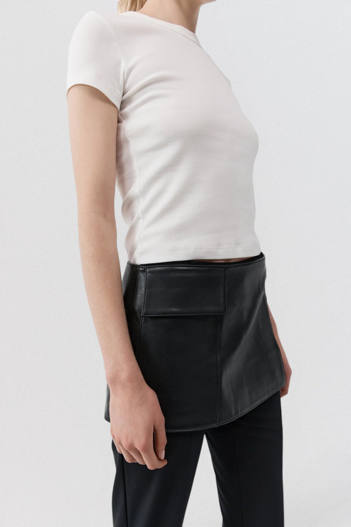 ST. AGNI Utility Skirt Belt in black lambskin leather with fold-over waistband and side cut-out detail