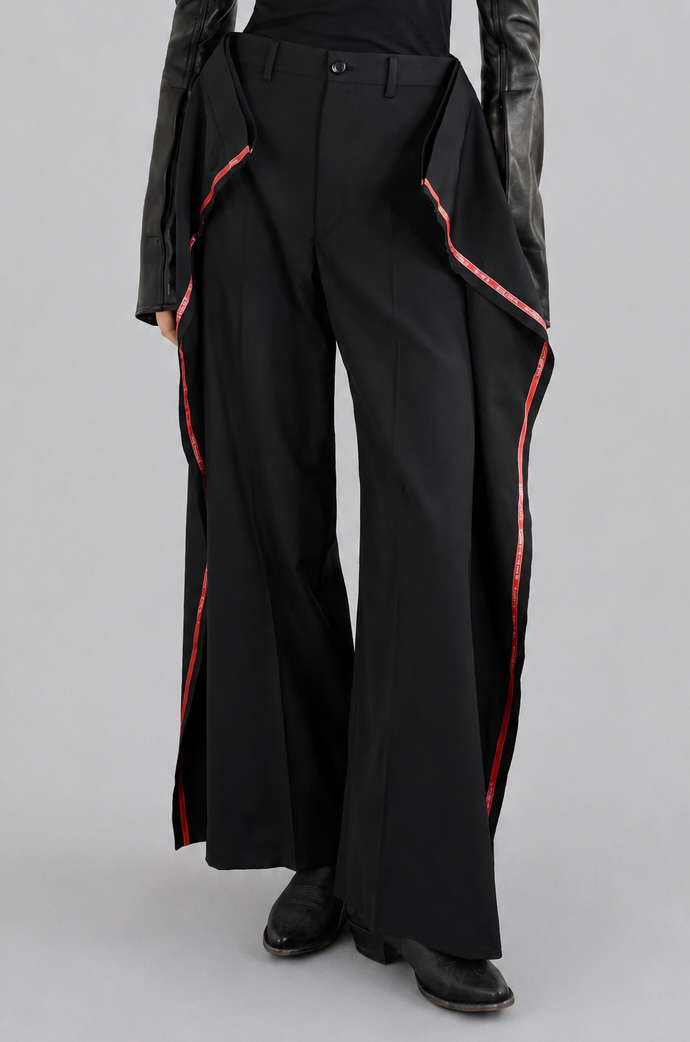 Junya Watanabe SS26 Side Stripes Trousers, a person wearing a black outfit with red accents on a gray background