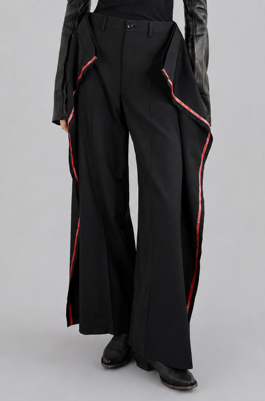 Junya Watanabe SS26 Side Stripes Trousers, a person wearing a black outfit with red accents on a gray background
